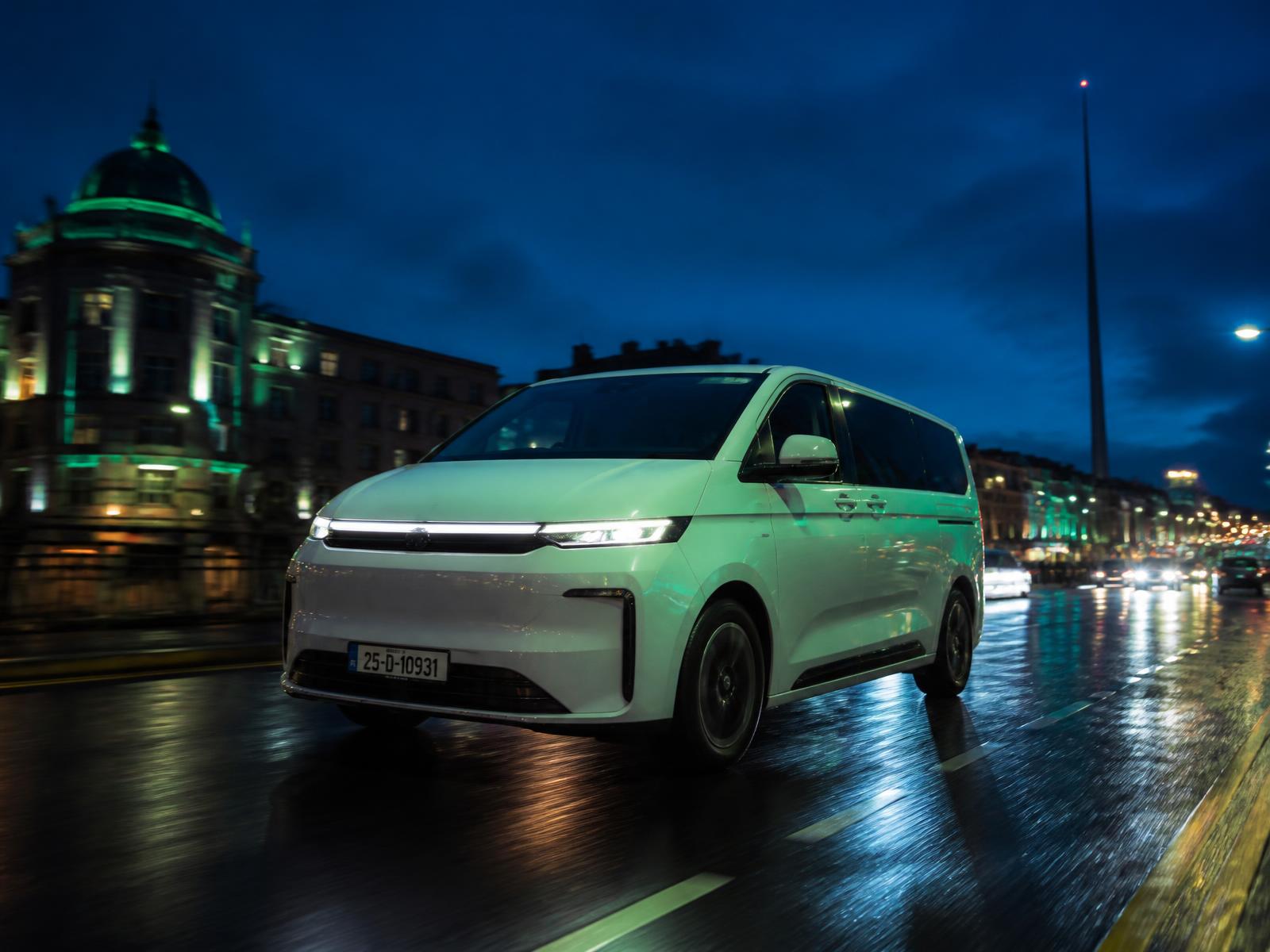 Modern white TransferUp van driving through Dublin city at night